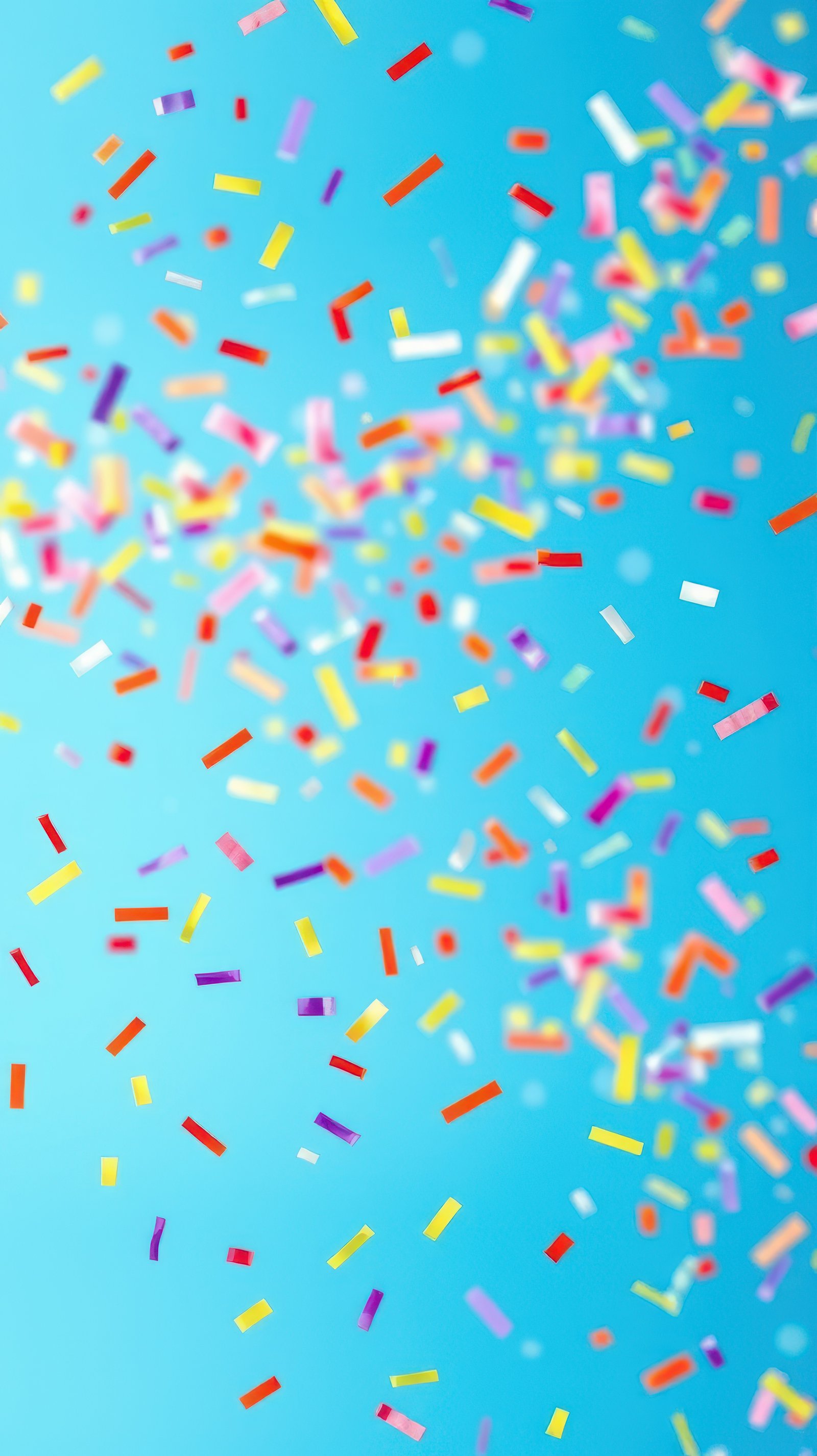 Colorful confetti falling against a bright blue background during a festive celebration or party
